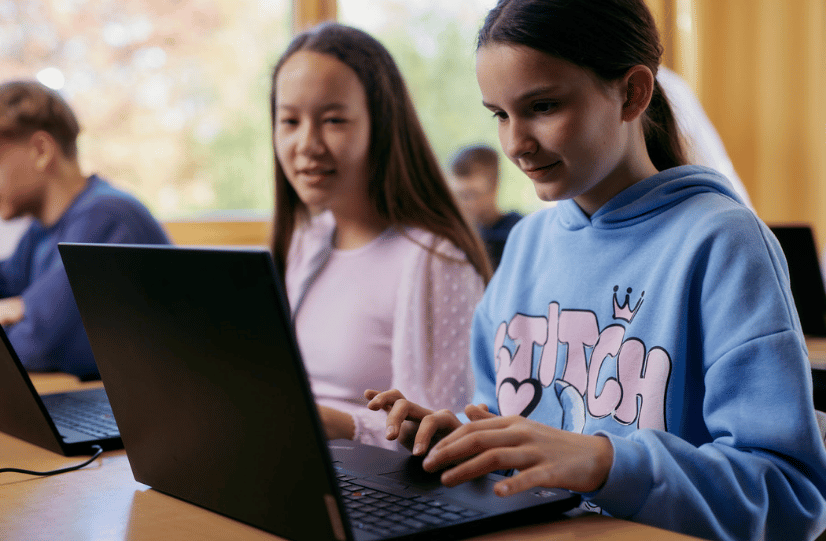 Zwei Schülerinnen arbeiten an Laptops in einem Klassenzimmer.