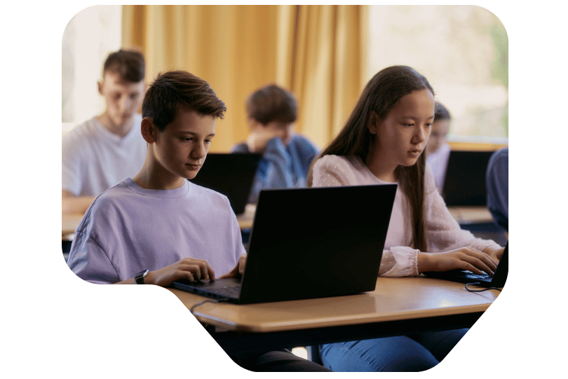 Schülerinnen und Schüler in einer Klasse mit Laptops.